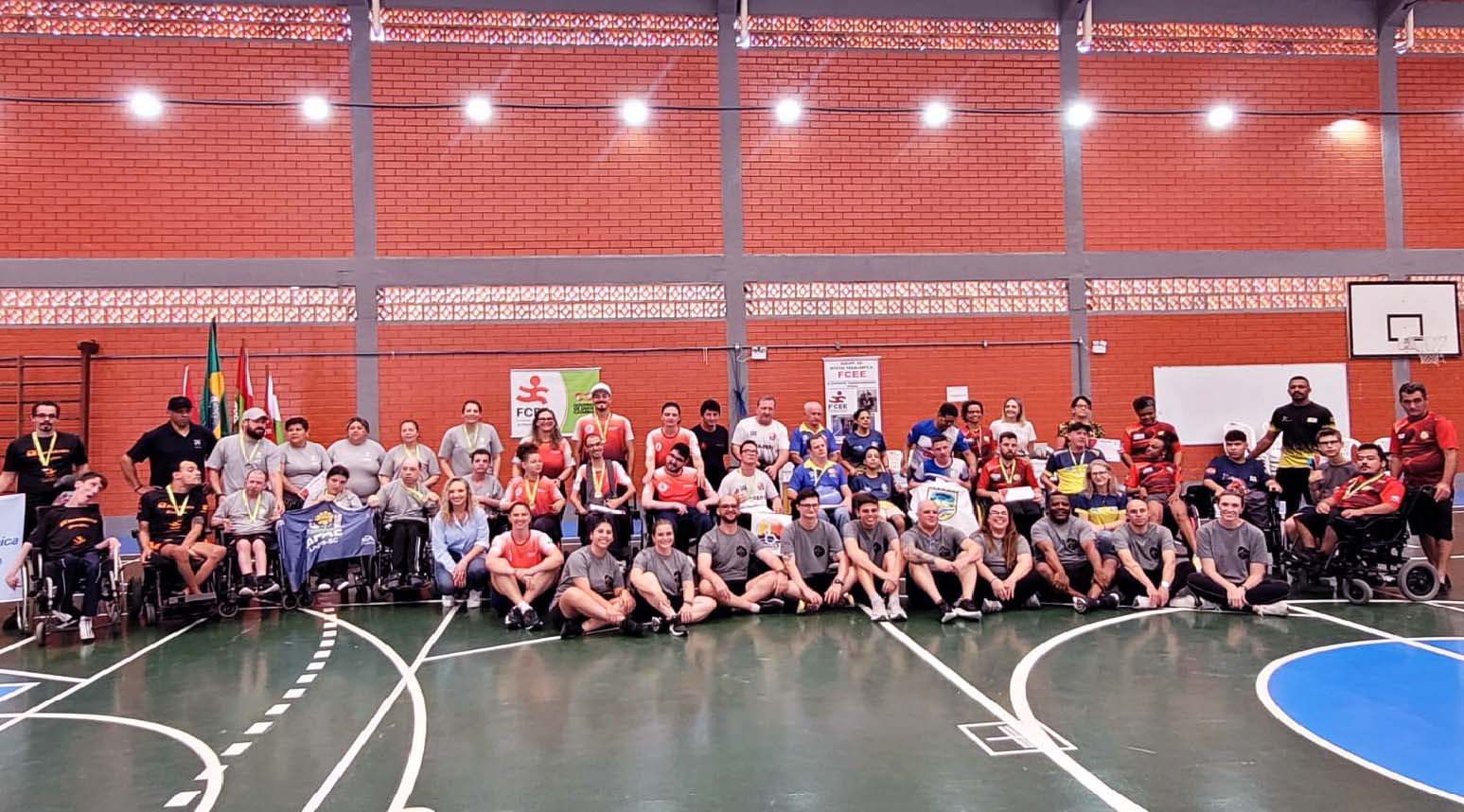 Foto de encerramento da etapa São José do Circuito Catarinense de Bocha Paralímpica 50 pessoas posam para foto em ginásio, cadeirantes, pessoas em pé