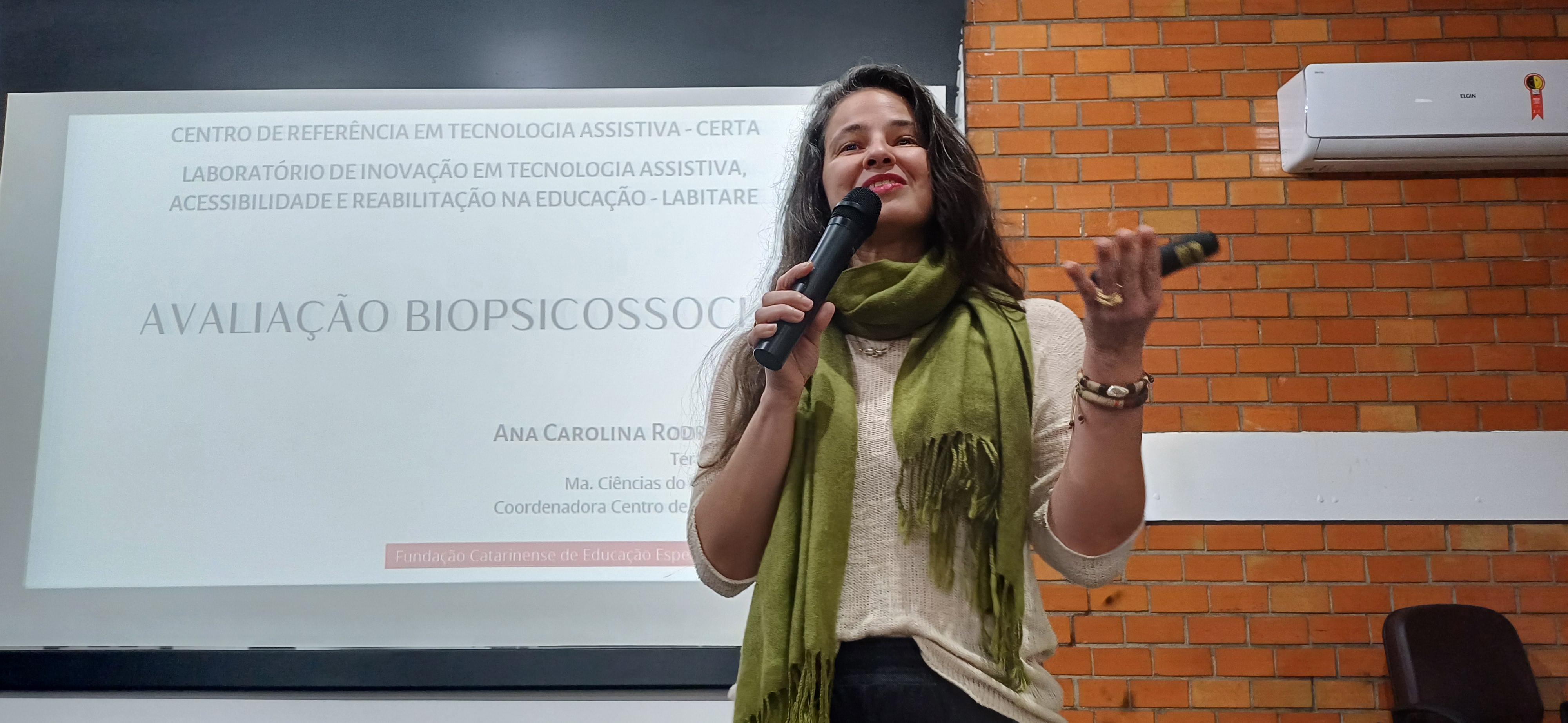 Palestra de abertura do III Seminário de Educação Inclusiva Mulher fala ao microfone sorrindo