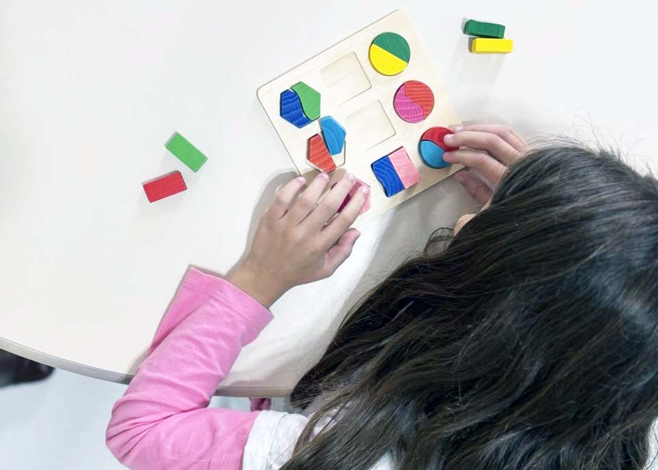 menina mexe em peças coloridas sobre mesa