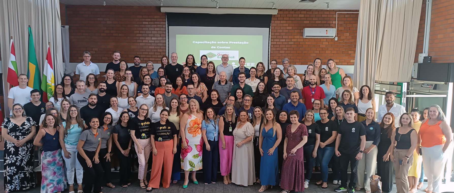 Participantes do curso de Prestação da Contas na FCEE grupo de cem pessoas posam para foto em auditório